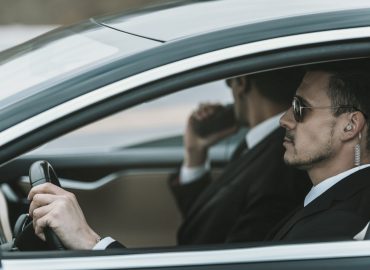 bodyguards with portable radio and security earpiece sitting in a car